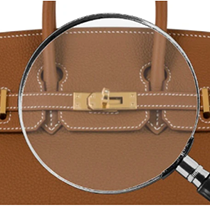 Brown leather handbag with a magnifying glass highlighting a gold clasp